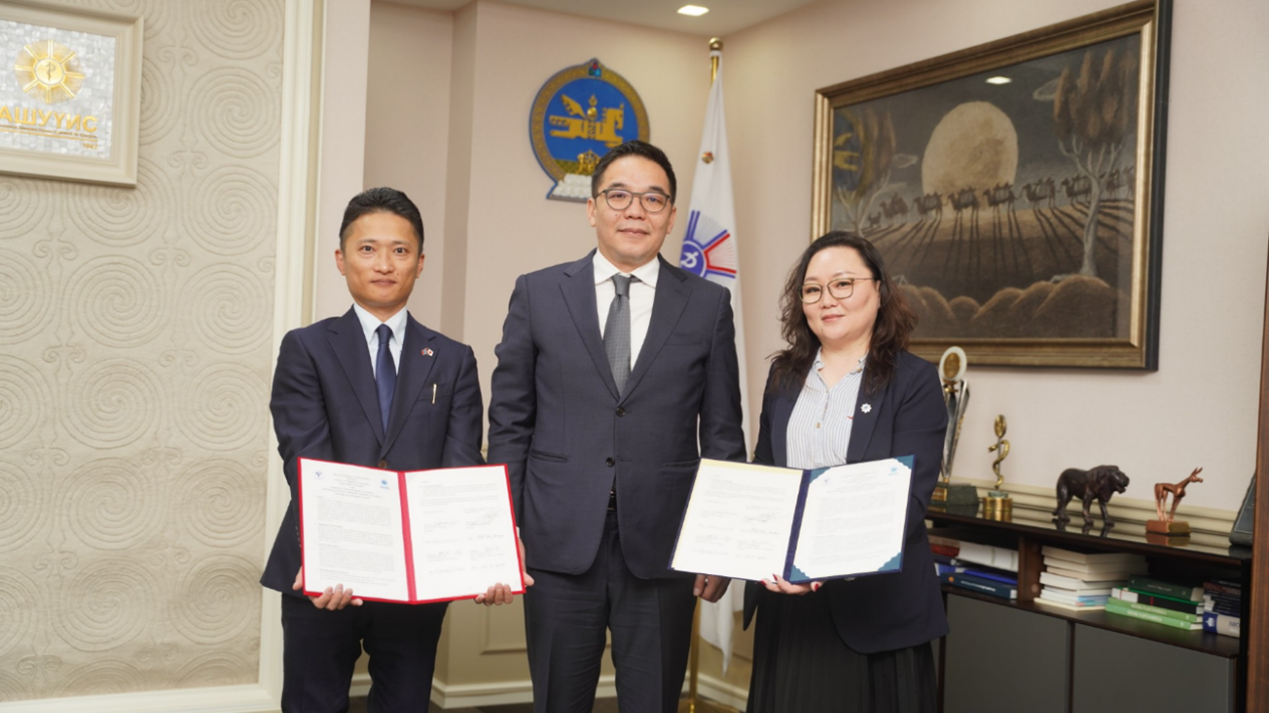 CRA署名後、署名文書を掲げる徳島大学 駒貴明研究教授（左）とモンゴル国立医科大学 Uurtuya大学院医学研究科長（右） 。両者の間には、モンゴル国立医科大学 Damdindorj学長（中）が立つ。
